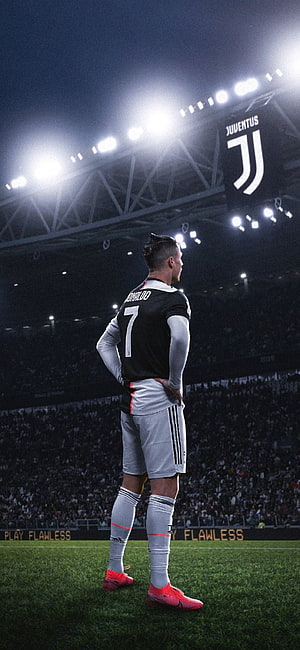 Cristiano Ronaldo in Juventus Kit Standing on the Pitch Under Stadium Lights HD phone wallpaper