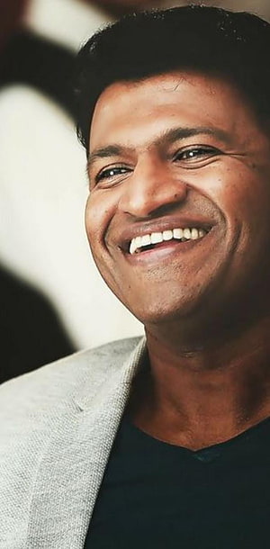 Puneeth Rajkumar smiling portrait in a light grey blazer and black shirt HD phone wallpaper
