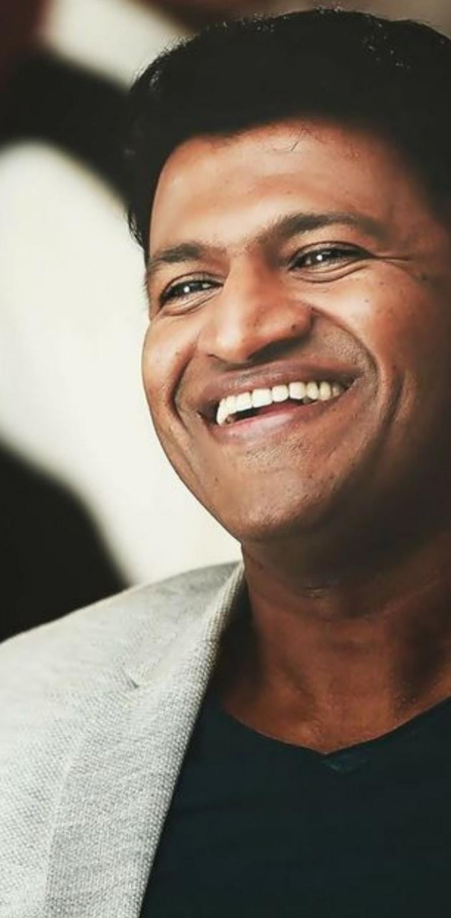 Puneeth Rajkumar smiling portrait in a light grey blazer and black shirt HD phone wallpaper