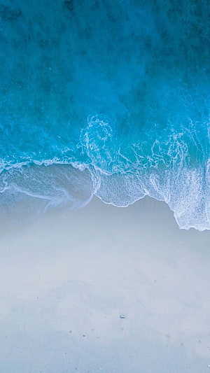 Aerial View of Turquoise Ocean Waves Lapping Against White Sandy Shore HD phone wallpaper