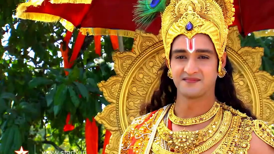 Krishna in ornate golden crown and jewelry with peacock feather and red ceremonial canopy HD wallpaper