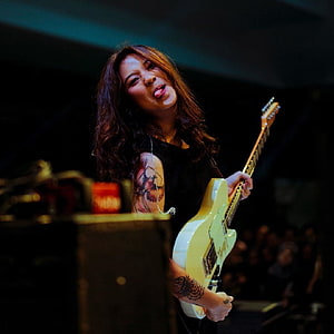 Danilla Riyadi performing live on stage with a white electric guitar HD phone wallpaper