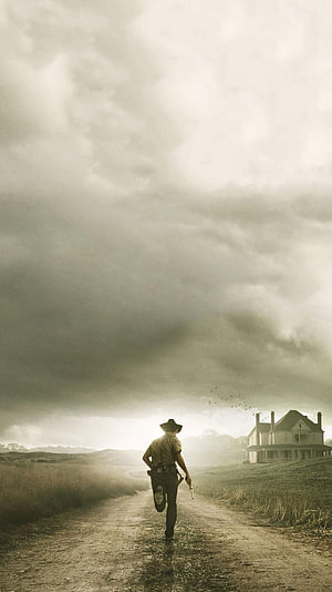 The Walking Dead Lone Figure Walking Toward Distant Manor Under Stormy Sky HD phone wallpaper