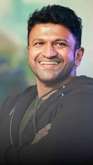 Punith Rajkumar smiling portrait in a black hoodie with arms crossed HD phone wallpaper