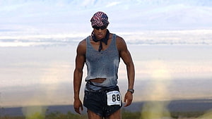 David Goggins Running in Desert Landscape Wearing American Flag Bandana and Race Bib HD wallpaper