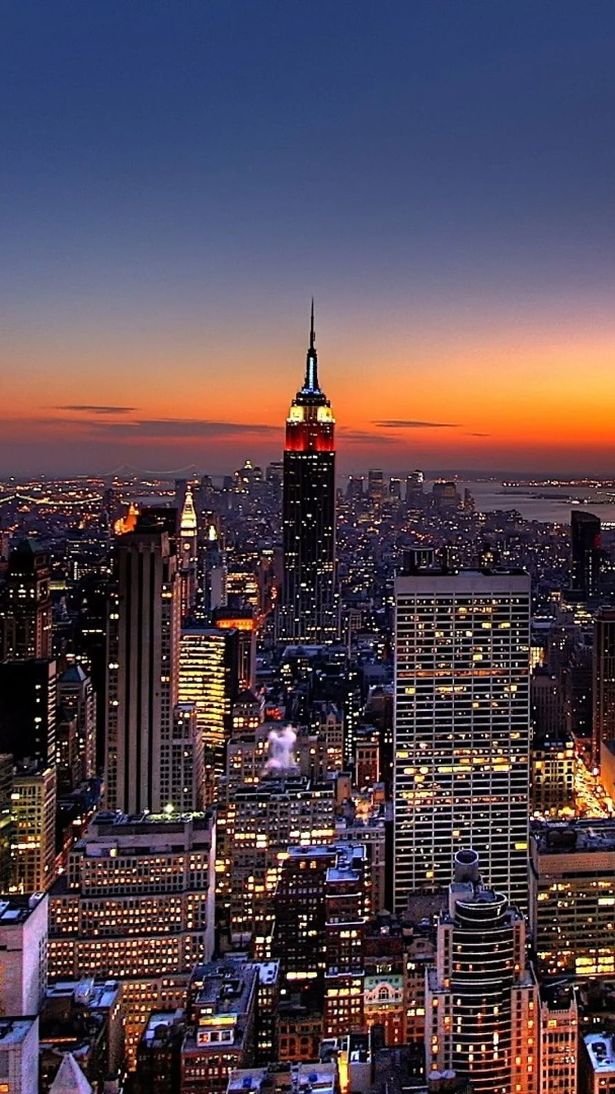 New York City Skyline at Dusk with Empire State Building Illuminated Against Orange Sunset HD phone wallpaper