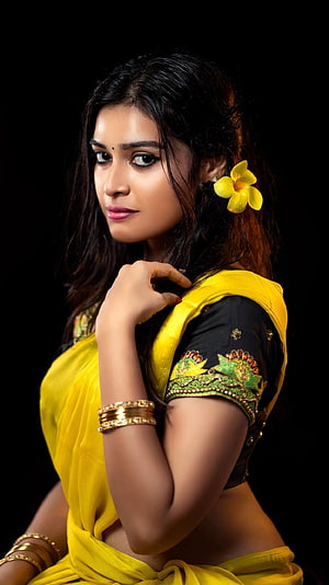 Dharsha Gupta in a vibrant yellow saree with floral hair accessory and gold bangles HD phone wallpaper