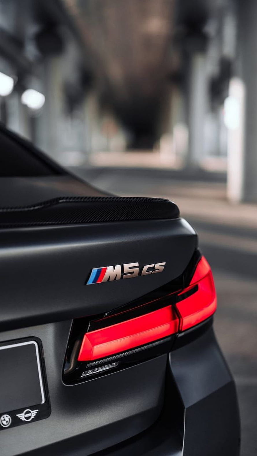 Close-up of the rear quarter panel and taillight on a black BMW M5 CS with carbon fiber spoiler HD phone wallpaper