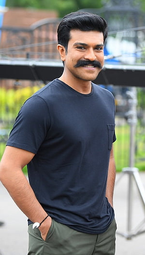 Ram Charan in a casual black t-shirt and olive trousers with a confident smile HD phone wallpaper