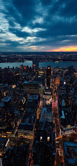 Aerial View of Manhattan Skyline at Dusk with Dramatic Clouds and City Lights HD phone wallpaper
