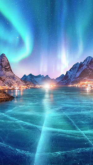 Vibrant Aurora Borealis Dancing Over Snow-Capped Mountains and Frozen Fjord at Night HD phone wallpaper