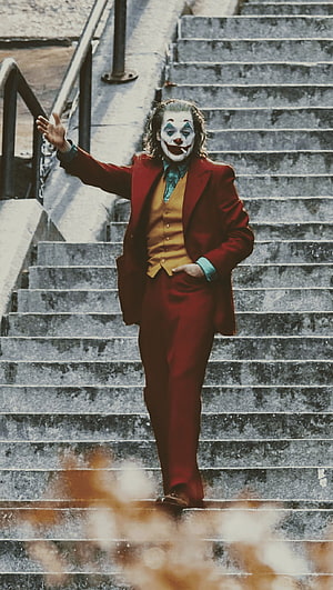 Joker in Red Suit Dancing Down Concrete Stairs with Clown Makeup HD phone wallpaper