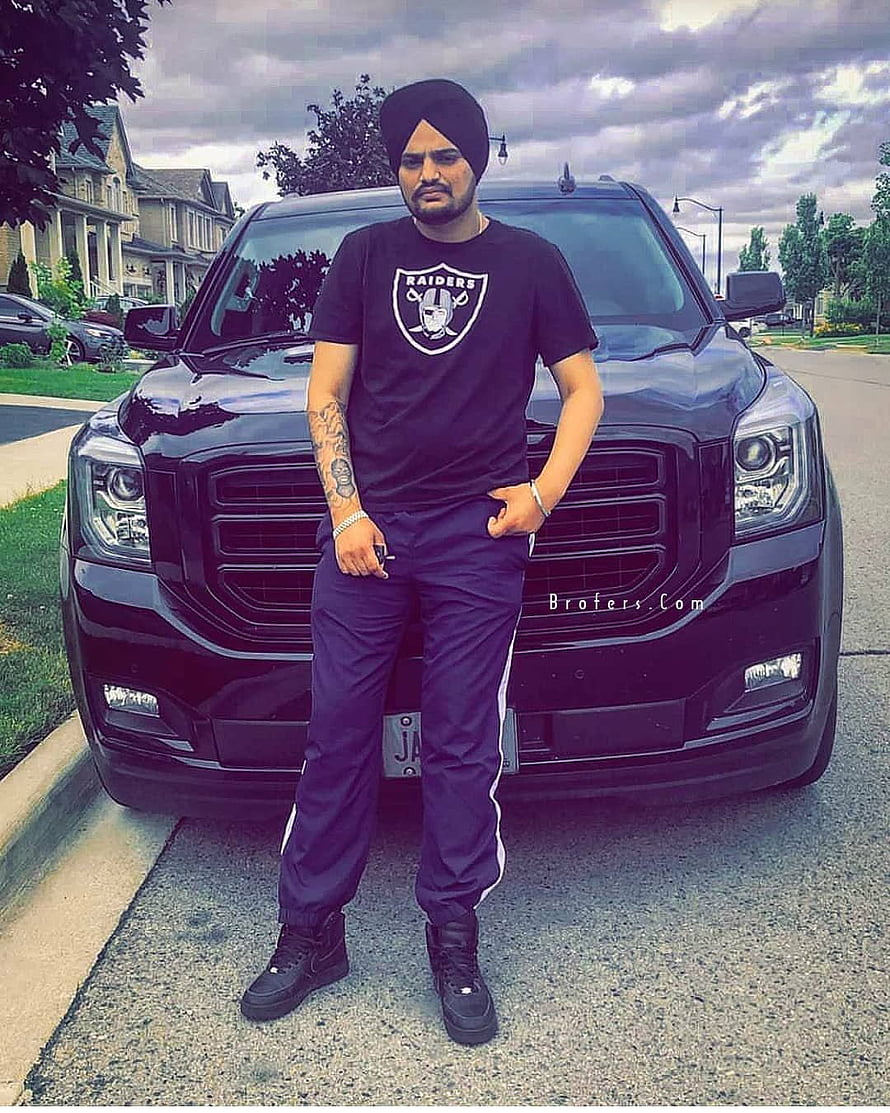 Sidhu Moose Wala in Black Turban and Raiders T-Shirt Standing Before a Black SUV HD phone wallpaper