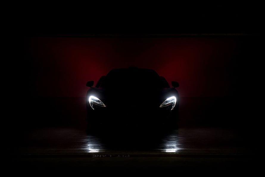McLaren P1 Supercar Silhouette with Glowing Headlights in Dark Red Atmosphere HD wallpaper