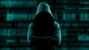 Silhouette of a hooded hacker with crossed arms against a digital code background HD wallpaper