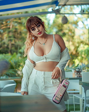 Ankita Dave in White Summer Outfit with Retro Phone Purse at Outdoor Cafe HD phone wallpaper
