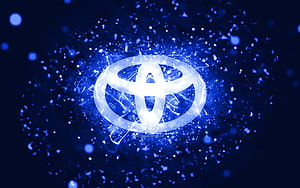 Glowing Toyota emblem surrounded by electric blue particles and neon light effects on a dark abstract background HD wallpaper