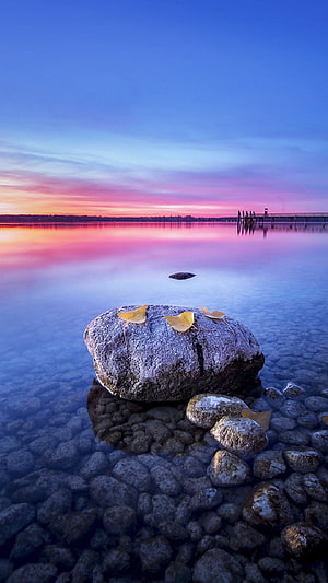 Serene Lake Sunset with Large Rock and Golden Leaves in Shallow Water HD phone wallpaper