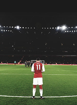 Mesut Özil in Arsenal Kit Standing on the Pitch at Night Under Stadium Lights HD phone wallpaper