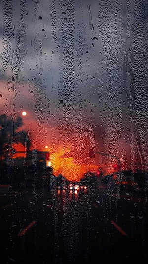 Moody Rainy Sunset View Through a Wet Car Windshield with Blurred City Lights HD phone wallpaper