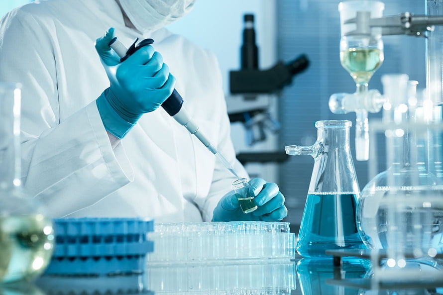 Scientist in white coat using a pipette to transfer liquid into a test tube in a modern laboratory HD wallpaper