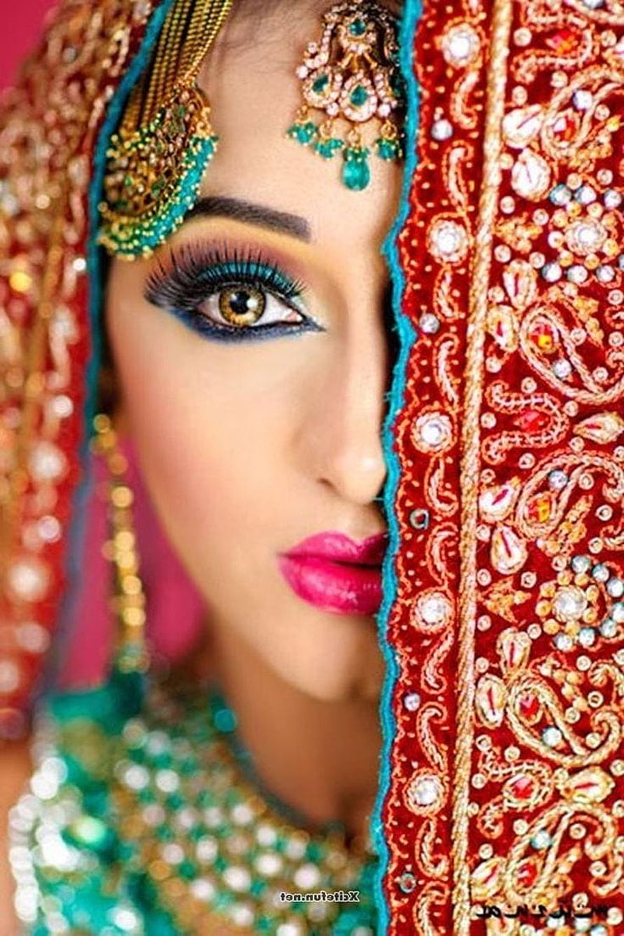 Close-up portrait of an Indian bride wearing ornate red and gold embroidered dupatta with traditional jewelry HD phone wallpaper