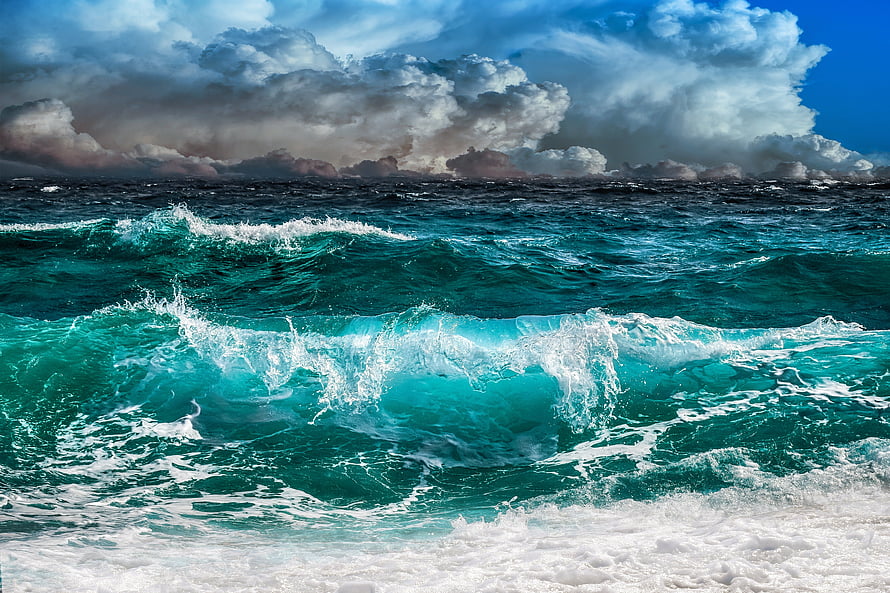 Turbulent turquoise ocean waves crashing under a dramatic stormy sky with towering cumulus clouds HD wallpaper