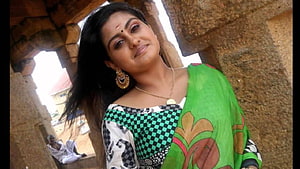 Indian woman in green sari and gold jewelry posing at a stone temple HD wallpaper