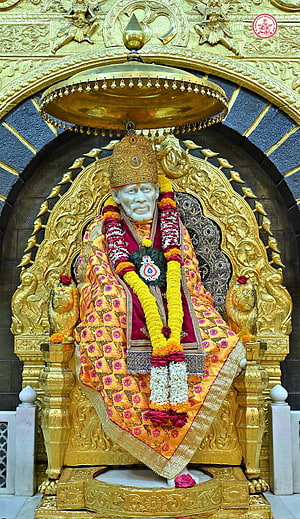 Sai Baba Temple Idol Adorned in Golden Garments and Marigold Garlands HD phone wallpaper