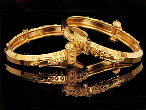 Elegant Gold Bangle Bracelets with Intricate Floral Engraving on Black Background HD wallpaper