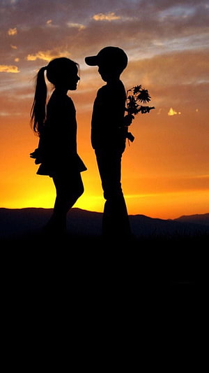 Silhouette of a couple standing face to face at sunset with flowers HD phone wallpaper