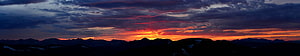 Dramatic Mountain Sunset Panorama with Fiery Orange Sky and Dark Silhouetted Peaks HD wallpaper