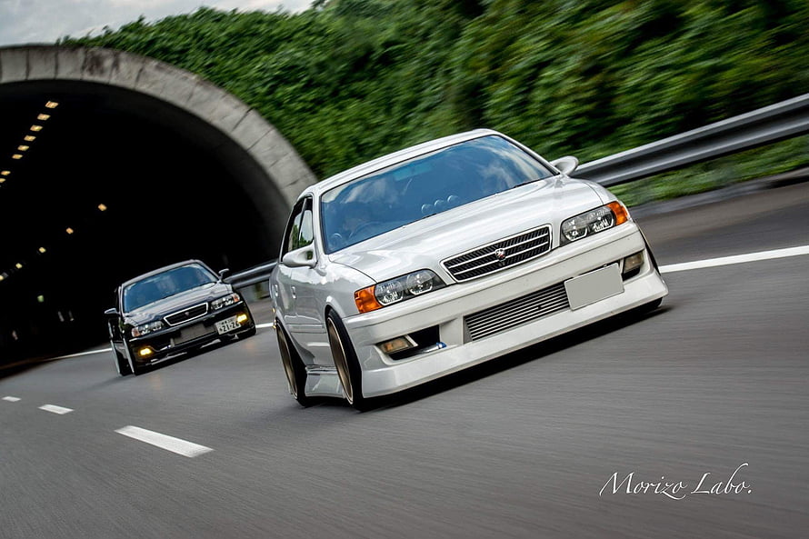 White Toyota Chaser JZX100 and Black Sedan Cruising on Japanese Highway HD wallpaper