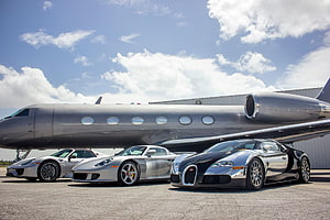 Luxury Supercars and Private Jet Parked on Tarmac Under Blue Sky HD wallpaper