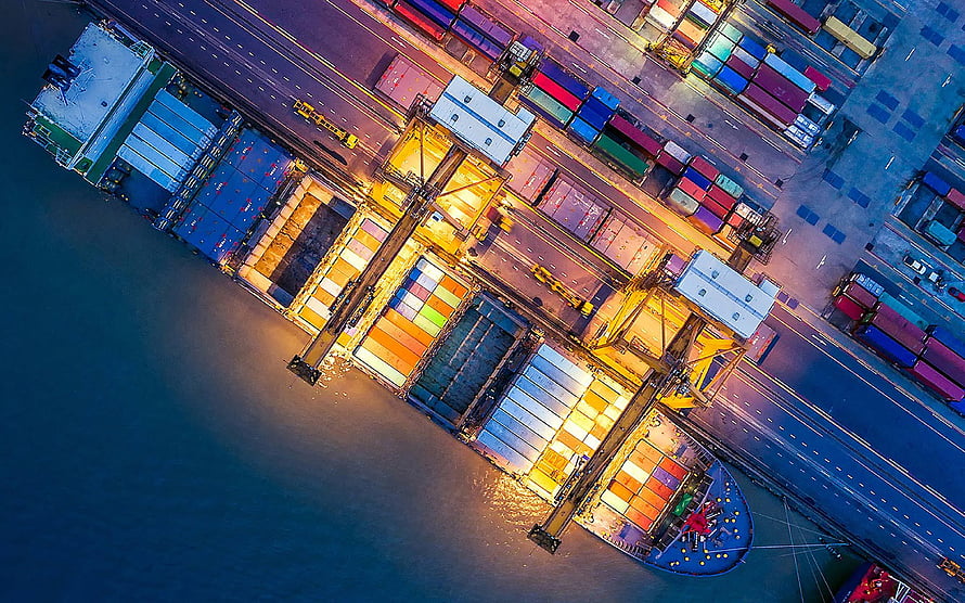 Aerial View of a Busy Container Port at Dusk with Colorful Cargo Ships and Cranes HD wallpaper