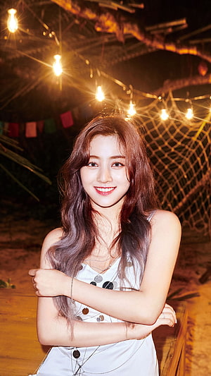Jihyo from Twice in a white dress under warm string lights at a tropical night setting HD phone wallpaper