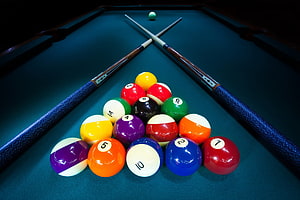 Rack of Billiard Balls and Crossed Cues on a Green Felt Pool Table HD wallpaper