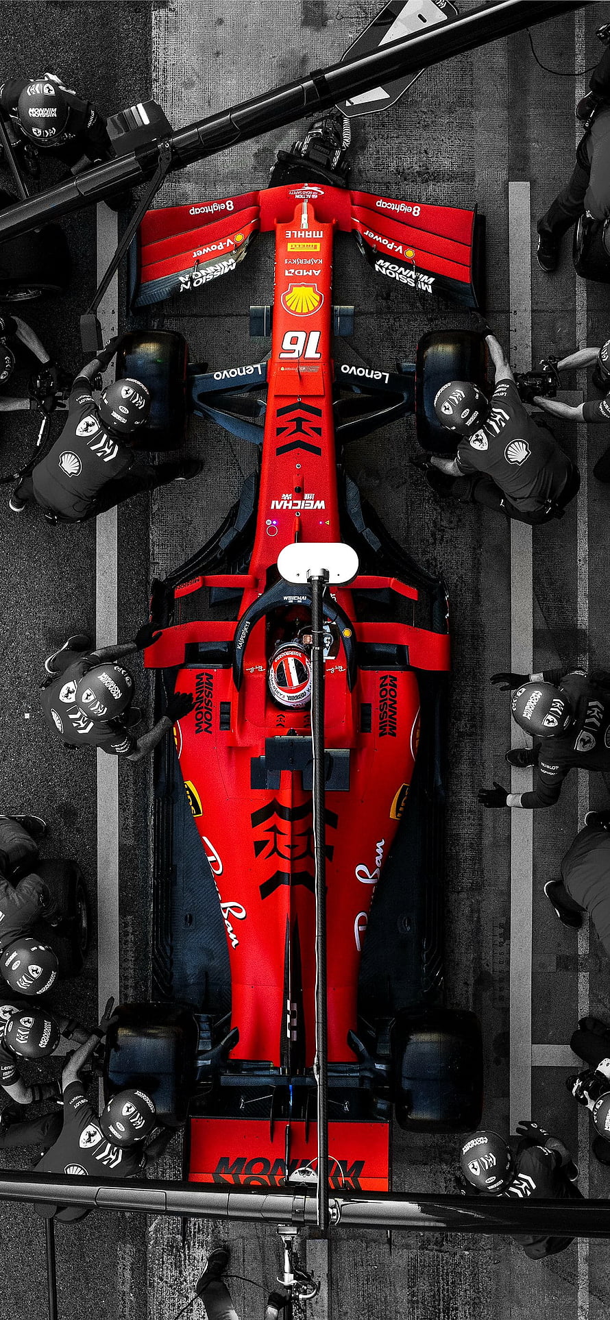 Top-down view of a red Ferrari Formula 1 car in the pit lane surrounded by mechanics HD phone wallpaper