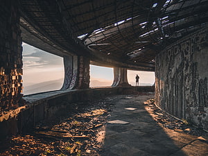 Silhouette of a lone figure inside the decaying Buzludzha monument at sunset HD wallpaper