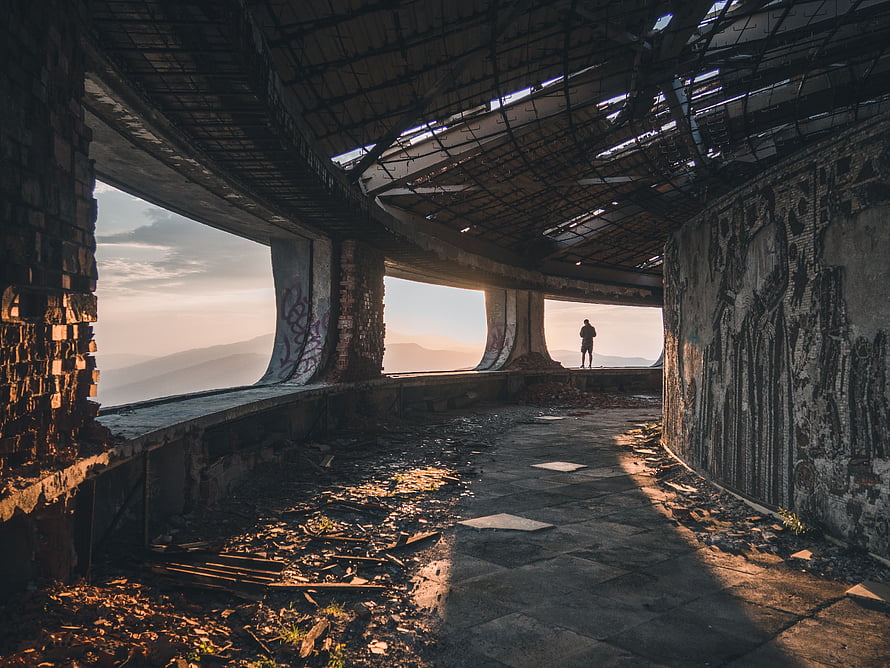 Silhouette of a lone figure inside the decaying Buzludzha monument at sunset HD wallpaper