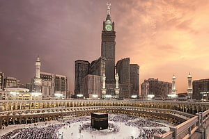 Grand Makkah Clock Tower and the Kaaba at sunset with pilgrims gathered in the courtyard HD wallpaper