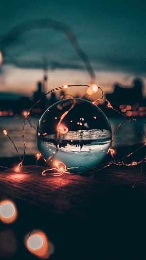 Crystal Lens Ball Capturing City Skyline at Dusk with Warm Fairy Lights HD phone wallpaper
