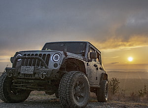 Muddy Jeep Wrangler on a Hilltop at Golden Hour Sunset HD wallpaper