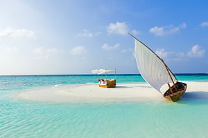 Traditional Dhow Sailboat Resting on White Sandbar in Turquoise Maldives Waters HD wallpaper