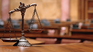 Ornate brass scales of justice on a wooden table in a formal courtroom setting HD wallpaper