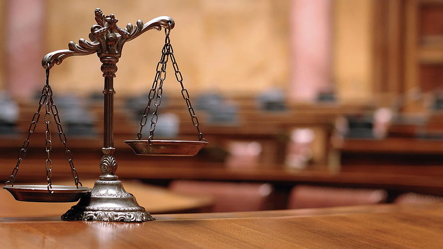 Ornate brass scales of justice on a wooden table in a formal courtroom setting HD wallpaper