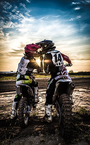 Two Motocross Riders Sharing a Moment at Sunset on a Dirt Track HD phone wallpaper