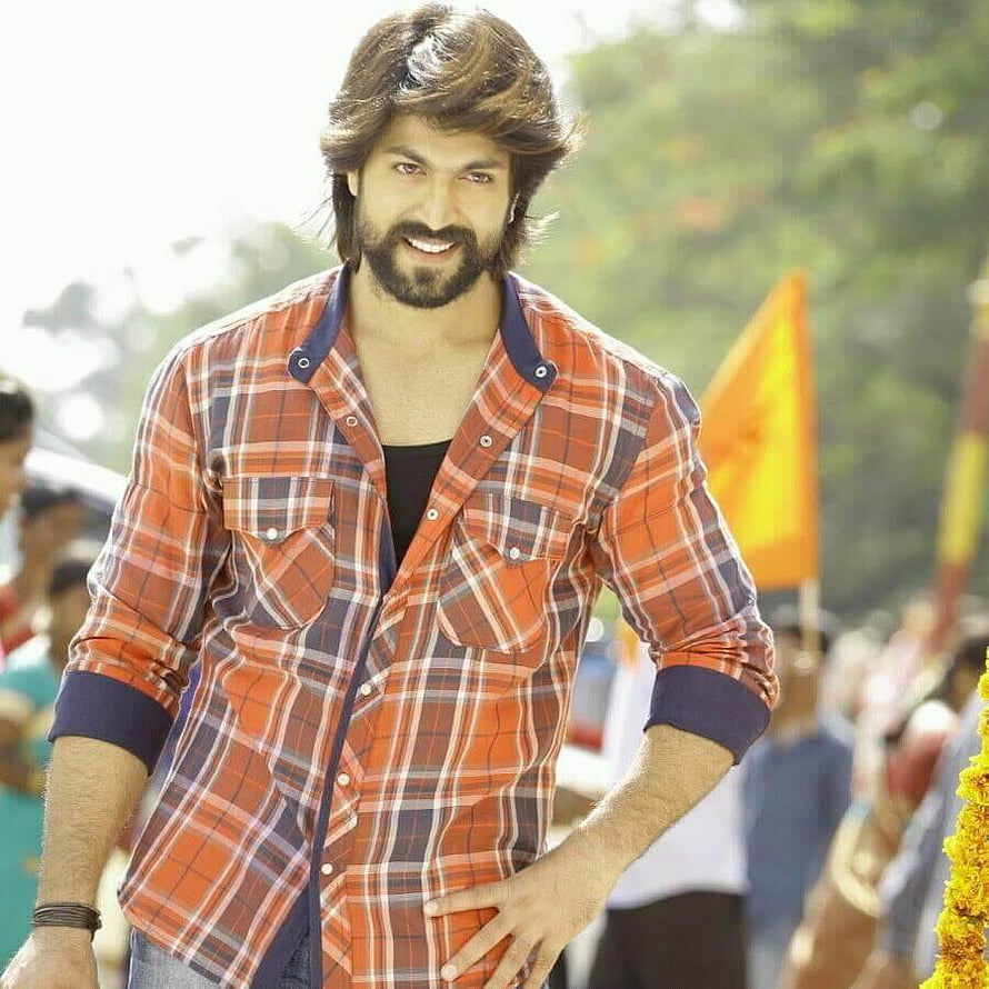 Yash in Orange Plaid Shirt at Outdoor Festival with Marigold Decorations HD phone wallpaper