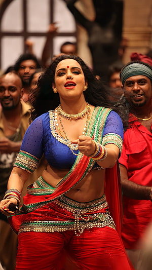 Swetha Menon in Vibrant Red and Blue Traditional Attire During a Dynamic Dance Performance HD phone wallpaper