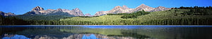 Panoramic Mountain Lake Reflection with Forested Hills and Clear Blue Sky HD wallpaper